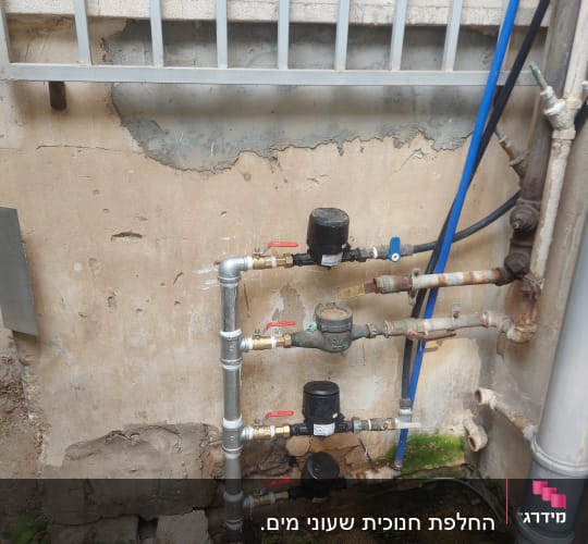 צינורות מים עם ברזים וכלי עבודה על הקרקע